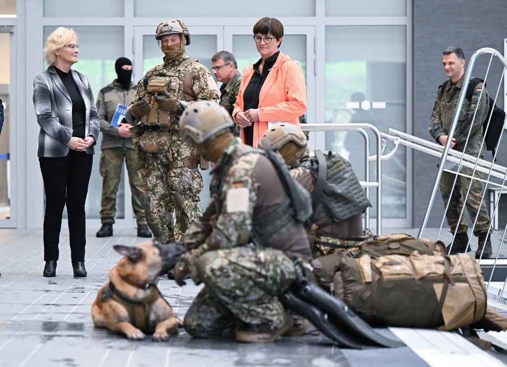 Bundesverteidigungsministerin Christine Lambrecht (l, SPD) sieht sich bei ihrem Besuch beim Kommando Spezialkräfte (KSK) in einer Schwimmhalle eine Ausbildungsübung mit einem Hund an.