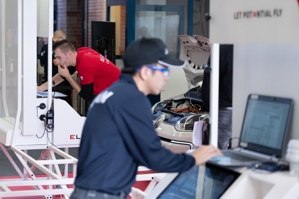 John Wiesemes (l) aus Belgien und Kaito Takasaki aus Japan arbeiten im Haus des KfZ-Gewerbes an einem Laptop.