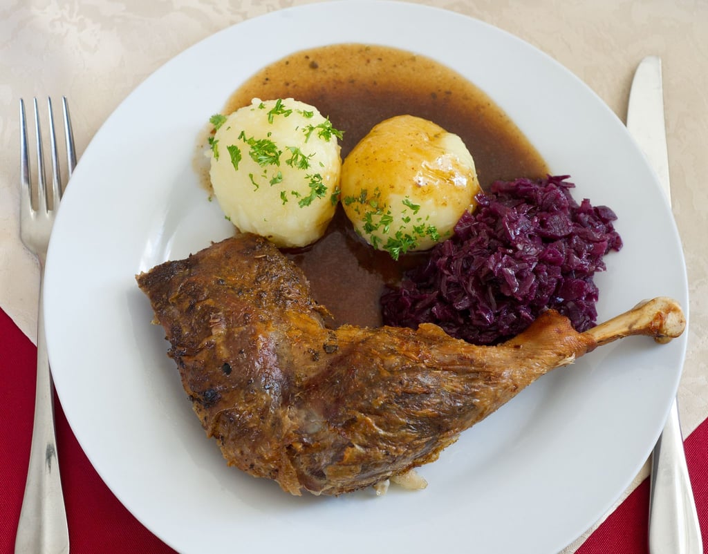 Ein Teller mit Klößen, Rotkohl und einer Gänsekeule steht in einer Gaststätte in Brandenburg auf dem Tisch.
