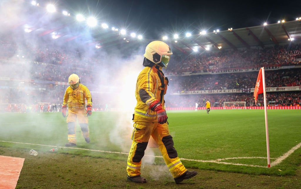 Feuerwehrleute löschen Bengalische Feuer während des Fußballspiels.