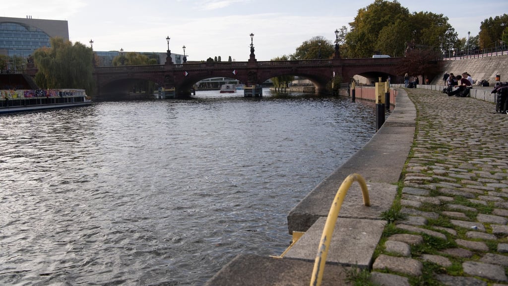Menschen sitzen unweit der Moltkebrücke an der Spree. In der Nacht zum Freitag war dort ein Hund in die Spree gesprungen, sein Besitzer hinterher. Doch sie kamen zunächst nicht wieder heraus.