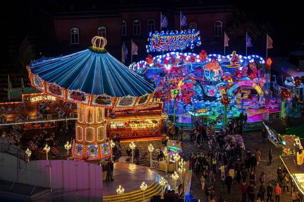 Die Fahrgeschäfte auf dem Freimarkt leuchten mit bunten Lichtern und Reklameschriftzügen.