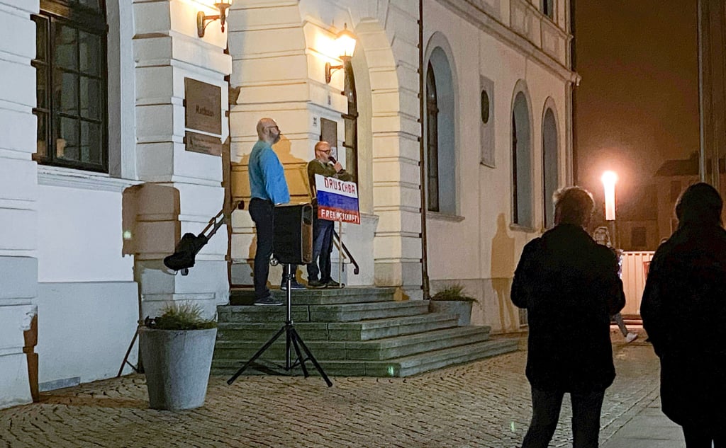 Ein Redner und Demonstrant trägt auf der Demo am Montagabend in Haldensleben ein Plakat mit Russlandflagge.