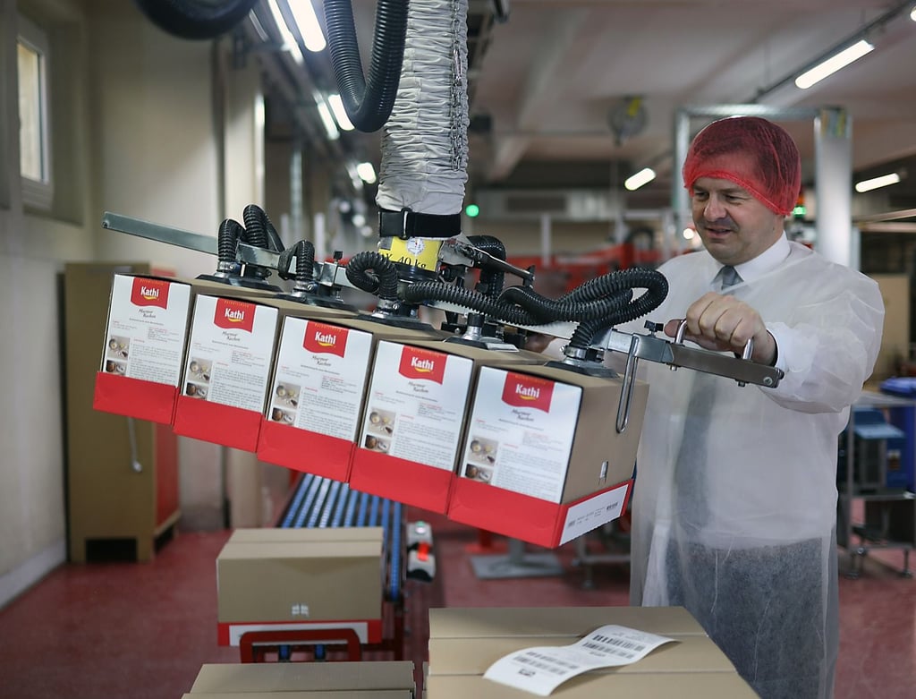 Bei Kathi am Band: Wirtschaftsminister Sven Schulze probiert sich an der Endverpackung von Marmorkuchen-Backmischungen aus.