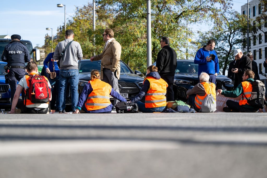 Klimaaktivisten haben sich am Karlsplatz in der Münchner Innenstadt auf die Fahrbahn geklebt und blockieren die Straße.