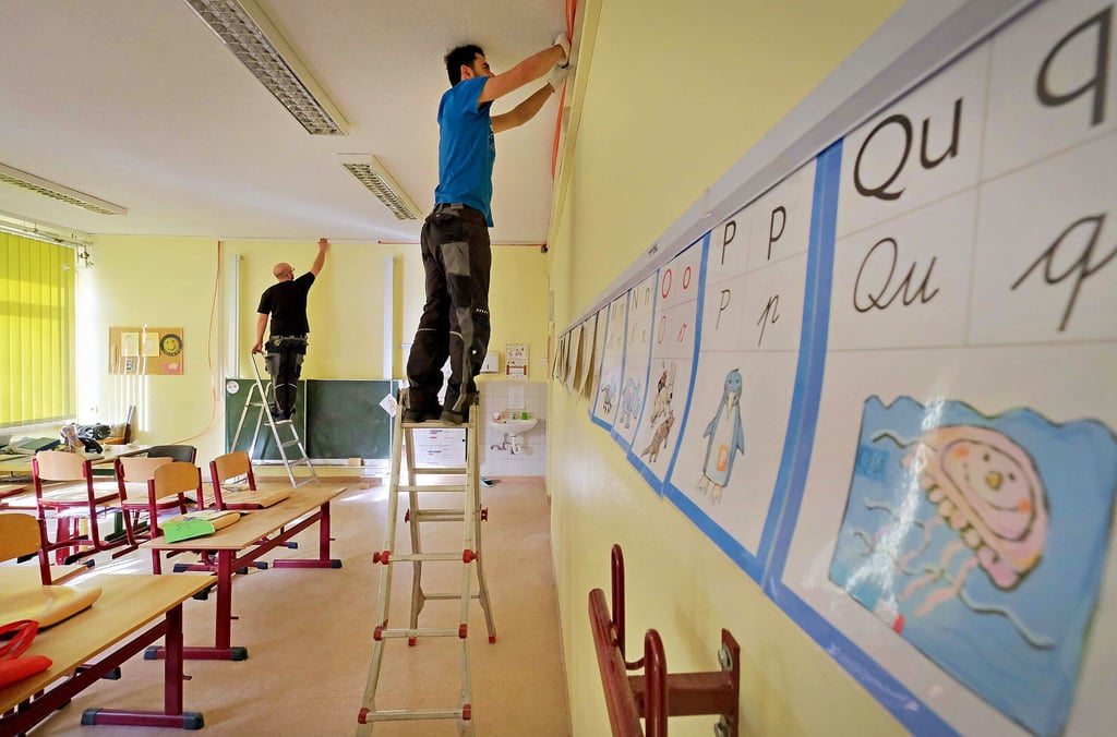 Max Friedrich (l.) und Azher Shaker, Mitarbeiter der Firma Elektro-Dietrich, ziehen in der Grundschule Gossa Kabel für Whiteboards ein.