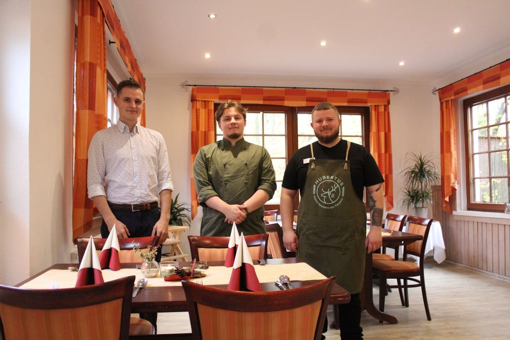 Geschäftsführer Lange (l-r), Koch Ranneberg und Service-Mitarbeiter Hagenow stehen in einem Speiseraum des Hotel-Restaurants „Hubertus“.
