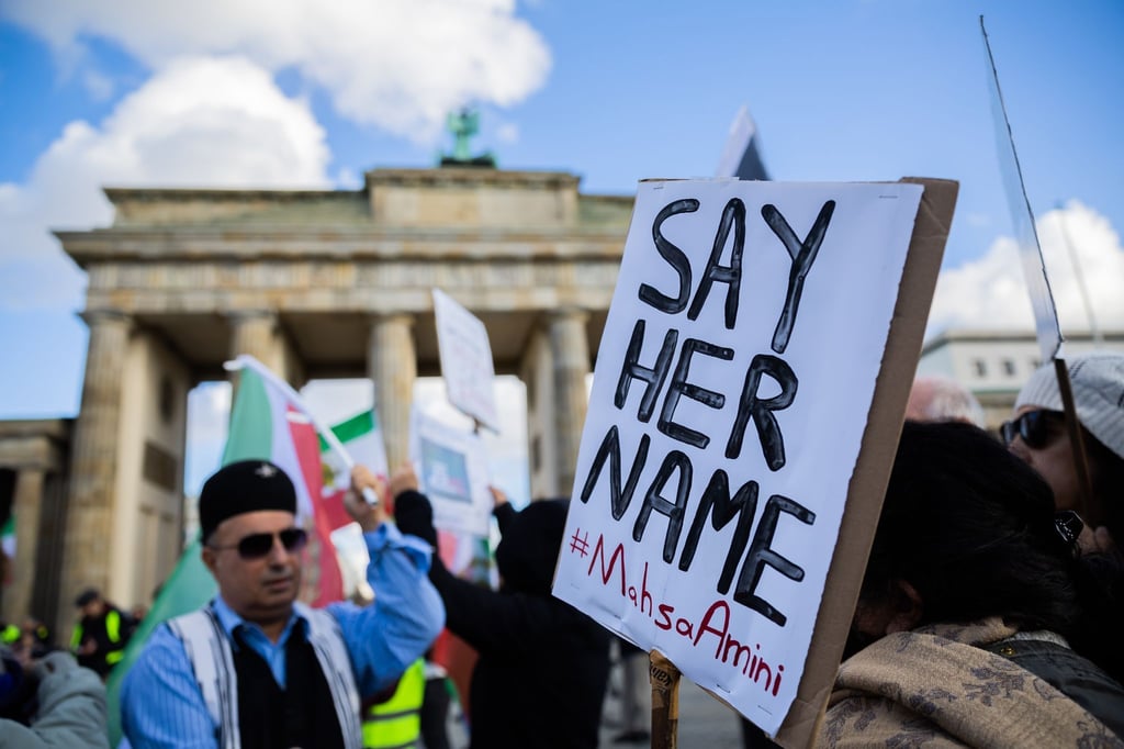„Say Her Name #Mahsa Amini“ steht bei einer Demonstration für Solidarität mit den Protestierenden im Iran am Brandenburger Tor auf einem Schild.