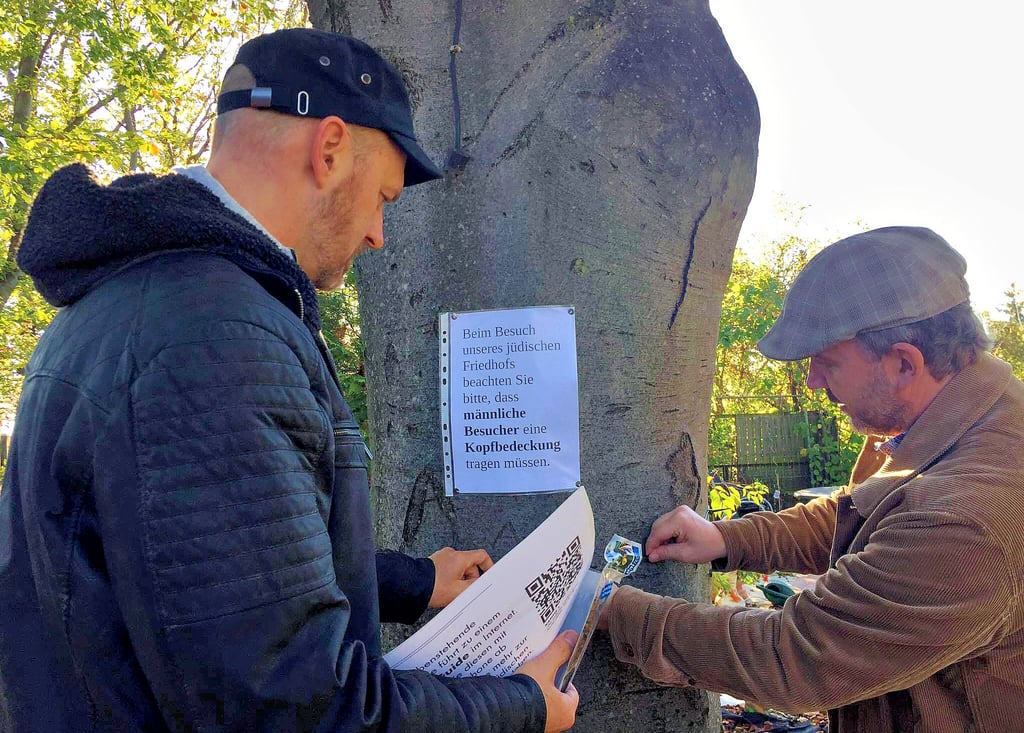 Lars Bremer (links) und Matthias Poeschel bringen per Kabelbinder die QR-Codes an die Bäume – eine Übergangslösung.