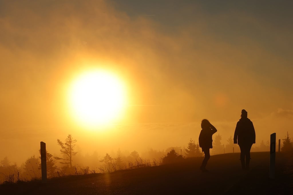 Bei aufgehender Sonne gehen Wanderer auf der Brockenstraße spazieren.