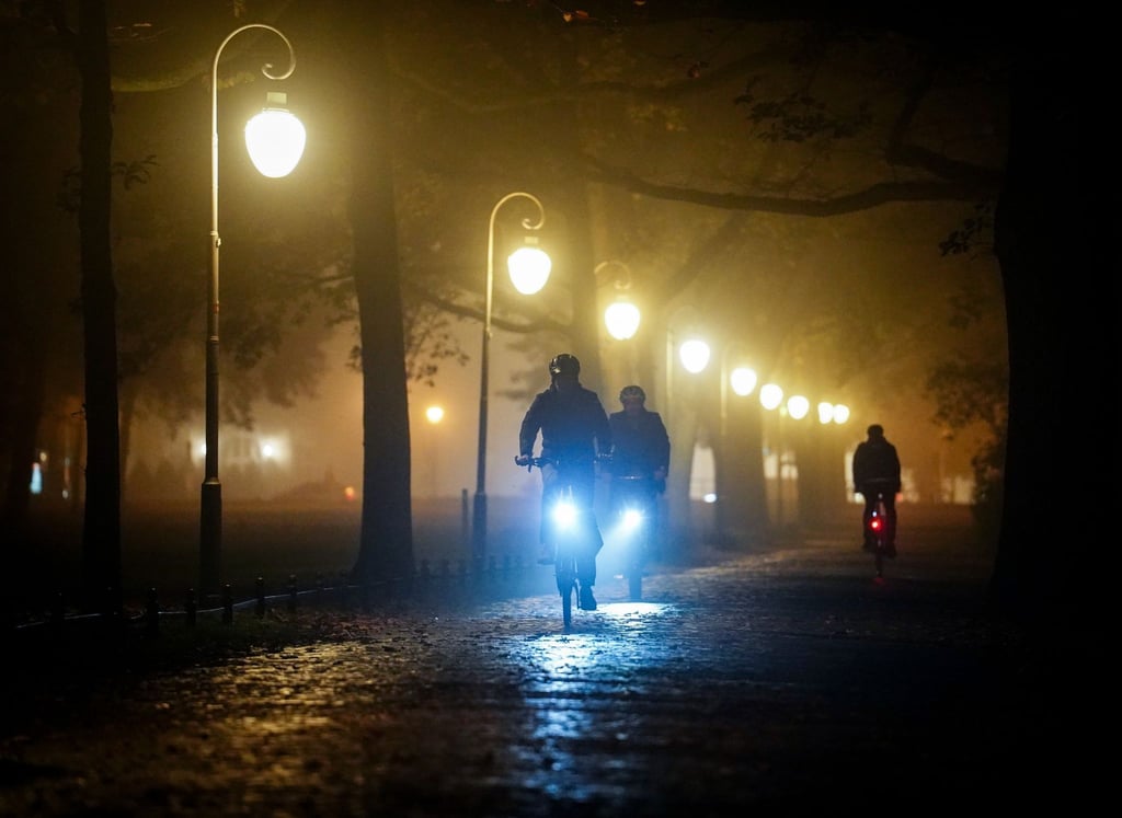 Radfahrer fahren am Abend durch den nebeligen Tiergarten.