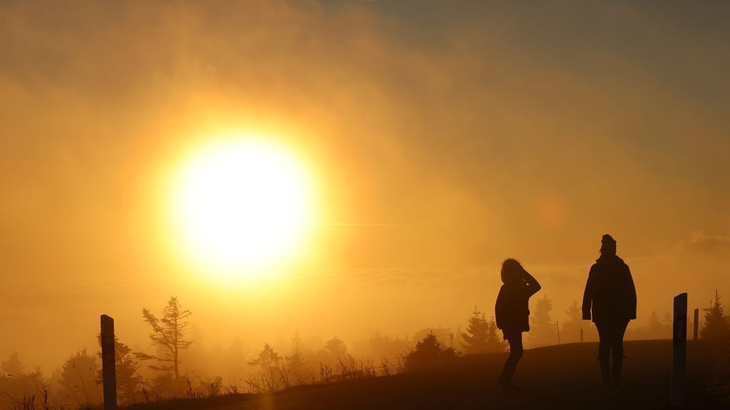 Bei aufgehender Sonne gehen Wanderer auf der Brockenstraße spazieren.