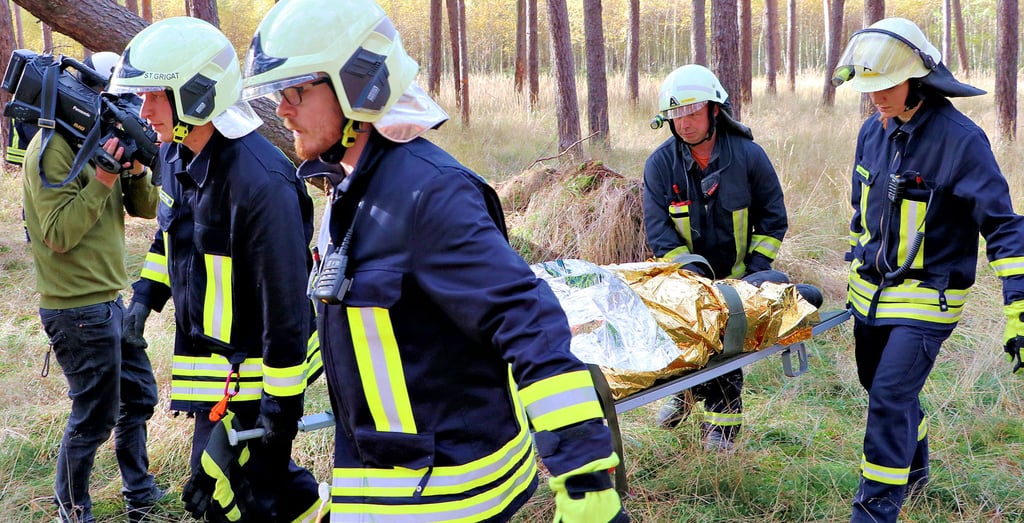 Feuerwehrleute tragen den „Verletzten“ aus dem Wald zwischen Gadegast und Naundorf.
