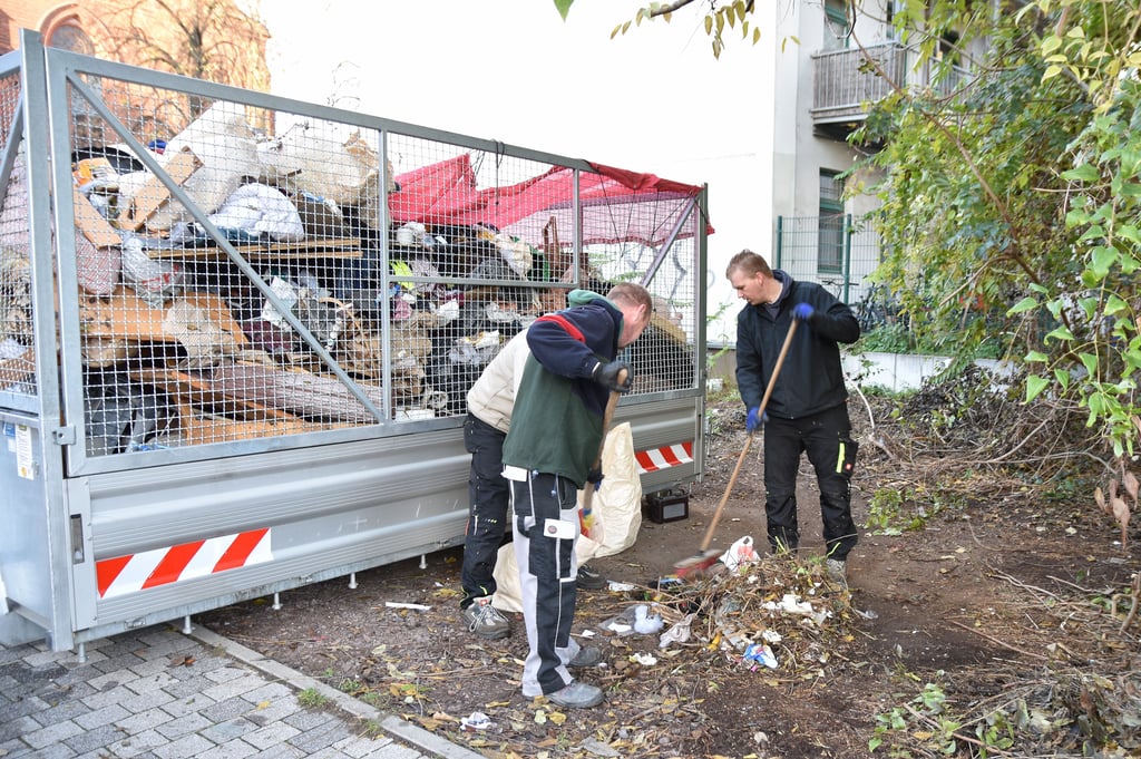 Reinigungsmitarbeiter beräumen die vermüllte Fläche an der Karl-Schmidt-Straße in Magdeburg-Buckau.