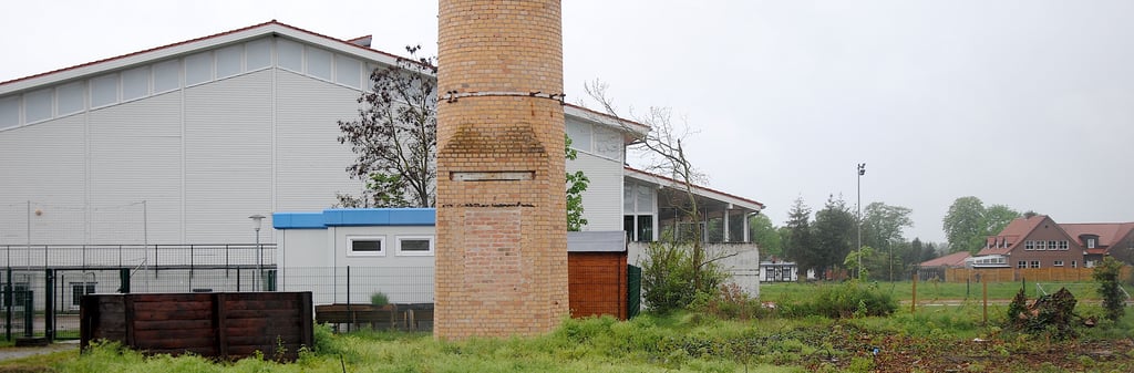Zwischen Sporthalle und Schornstein des ehemaligen Heizhauses steht bereits ein Container für den Hort. Bald könnte ein zweiter hinzukommen. Aber auch ein Modulbau oder eine Art Bauwagen sind als Übergangslösungen im Gespräch, um den Bedarf an Hortplätzen im nächsten Schuljahr abzudecken.