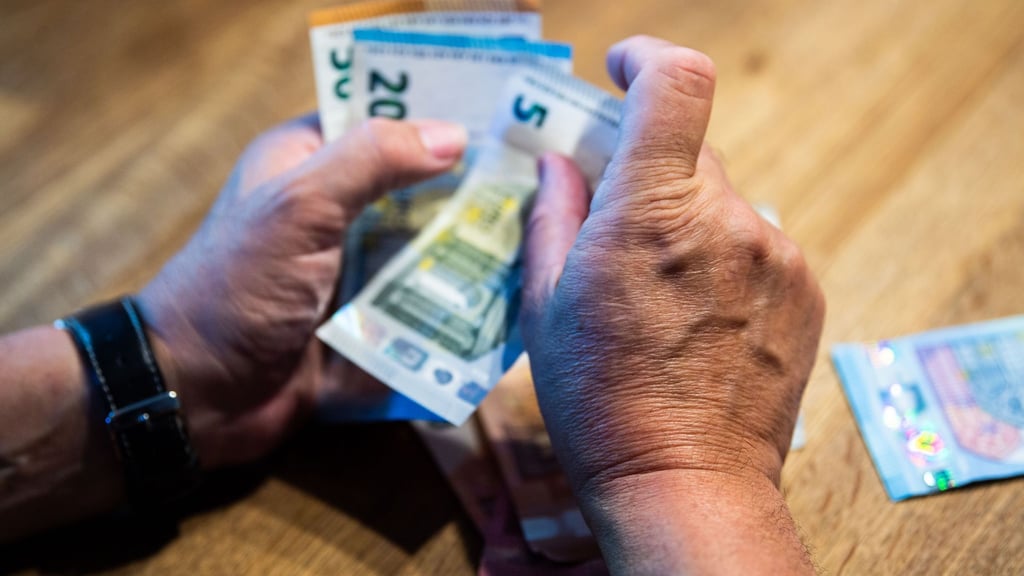 Ein Mann zählt Geld an einem Tisch.