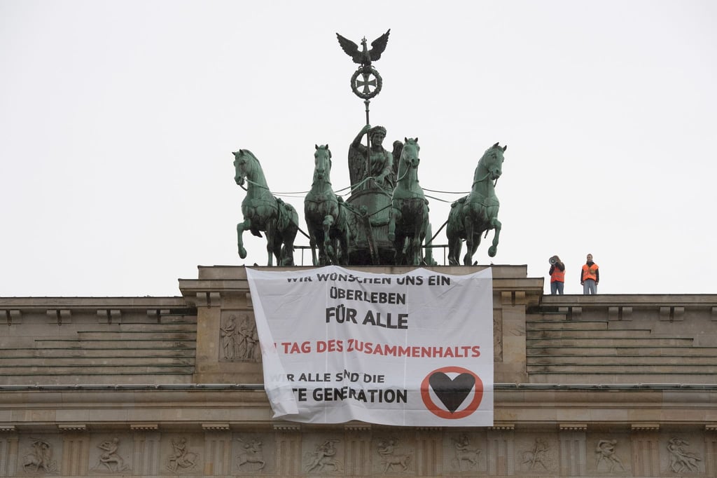 Ein Transparent mit dem Schriftzug „Wir wünschen uns ein Überleben für alle“ hängt am Brandenburger Tor.