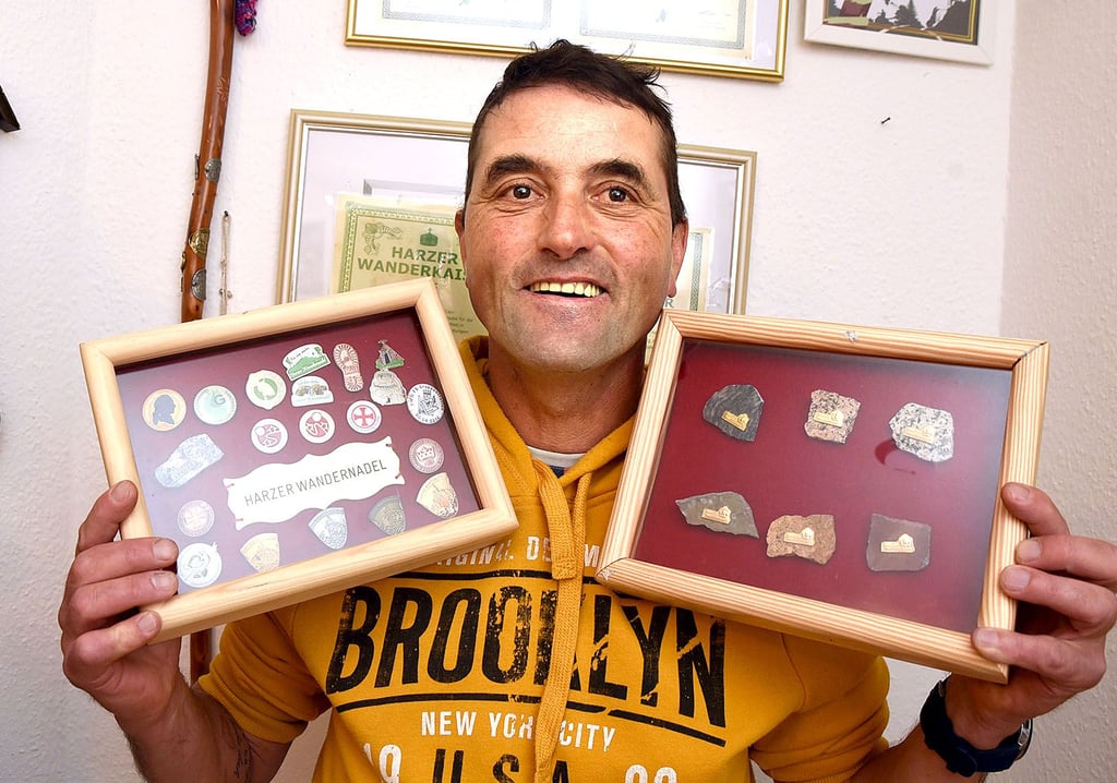 Jens Eichner aus Barby hat seine zahlreichen „Wanderorden“ eingerahmt. Für den Wanderkaiser (rechts) gibt es handgefertigte Broschen aus Harzer Gestein mit einer Goldplakette darauf.