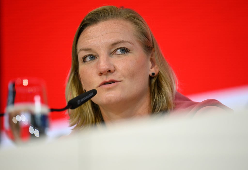 Nationalspielerin Alexandra Popp sitzt während einer Pressekonferenz auf dem Podium.
