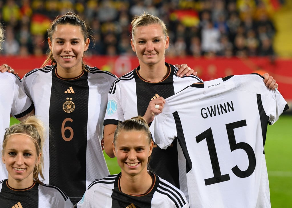 Alexandra Popp hält beim Mannschaftsfoto das Trikot der verletzen Giulia Gwinn in den Händen.
