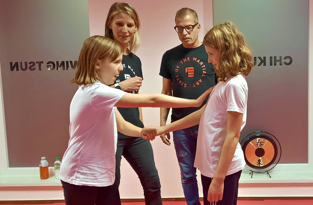 Kornelia Fröde und Thomas Karius zeigen Emilia, Myriel (v.l.n.r.) und den weiteren jungen Vereinsmitgleidern in der Kampfkunstschule Lützen, wie man sich im Notfall selbst verteidigt.