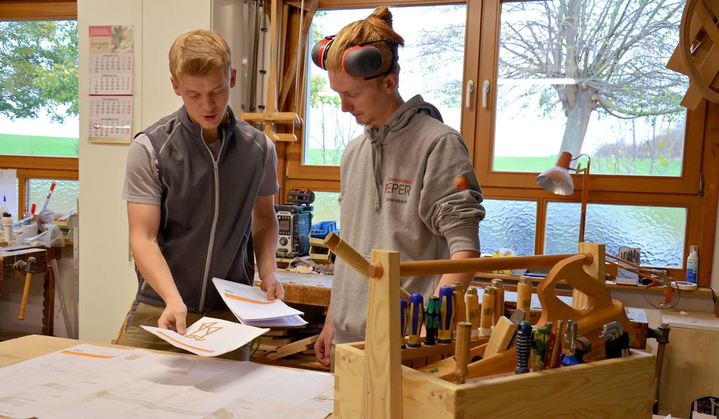 Lehrlingsausbilder Karsten Pieper (links) erklärt Azubi Mattes Geiersbach, wie die Zeichnung zu lesen ist. Auf dem Tisch steht die Werkzeugkiste, die der junge Mann selbst gebaut hat und die für eine gute Übersicht sorgt.