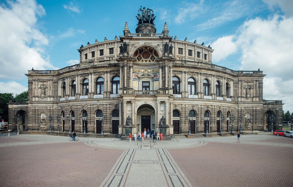 Touristen stehen vor der Semperoper in Dresden.