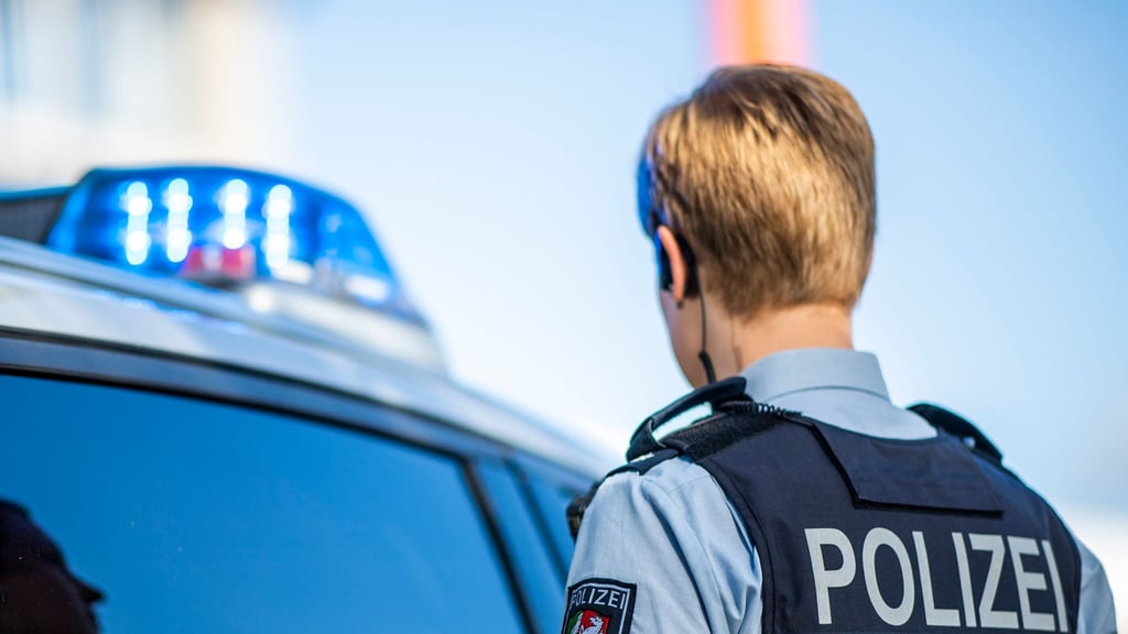 Eine Polizistin steht vor einem Streifenwagen.