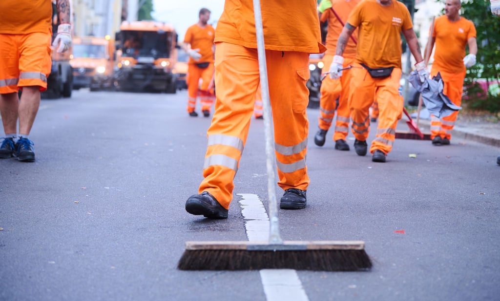 Mitarbeiter der Berliner Stadtreinigung (BSR) und Putzfahrzeuge reinigen die Straße direkt hinter dem „Zug der Liebe“.