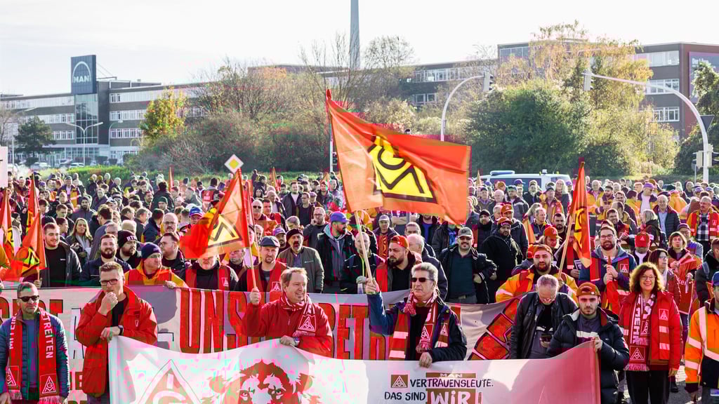 Kundgebungsteilnehmer zum Warnstreik der Metall- und Elektroindustrie stehen während der Kundgebung auf der Verkehrskreuzung „Kreuzung der Metallerinnen und Metaller“.