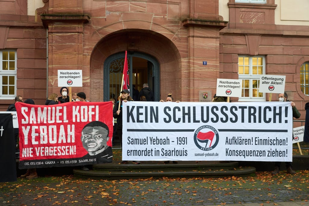 Demonstranten stehen vor dem Prozessbeginn am Eingang des Oberlandesgerichts.