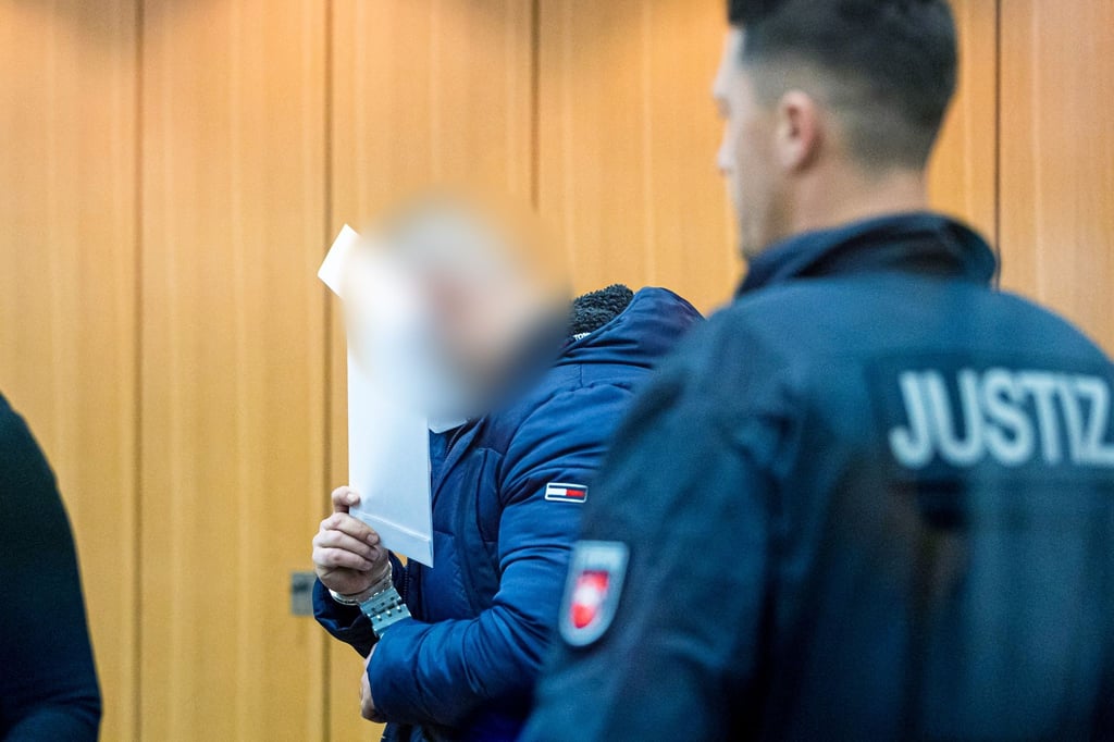 Der Angeklagte (l) steht bei Prozessauftakt in einem Saal vom Landgericht Braunschweig.