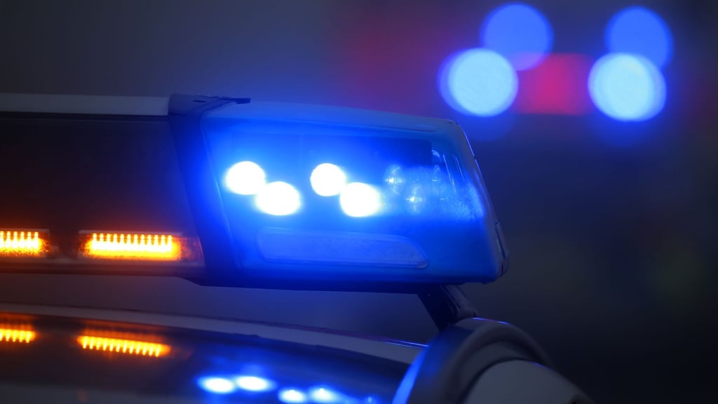 Ein Polizeiauto mit eingeschaltetem Blaulicht steht an einer Unfallstelle.