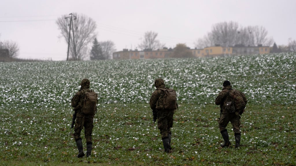 Polnische Soldaten suchen auf einem Acker nach Wrackteilen.