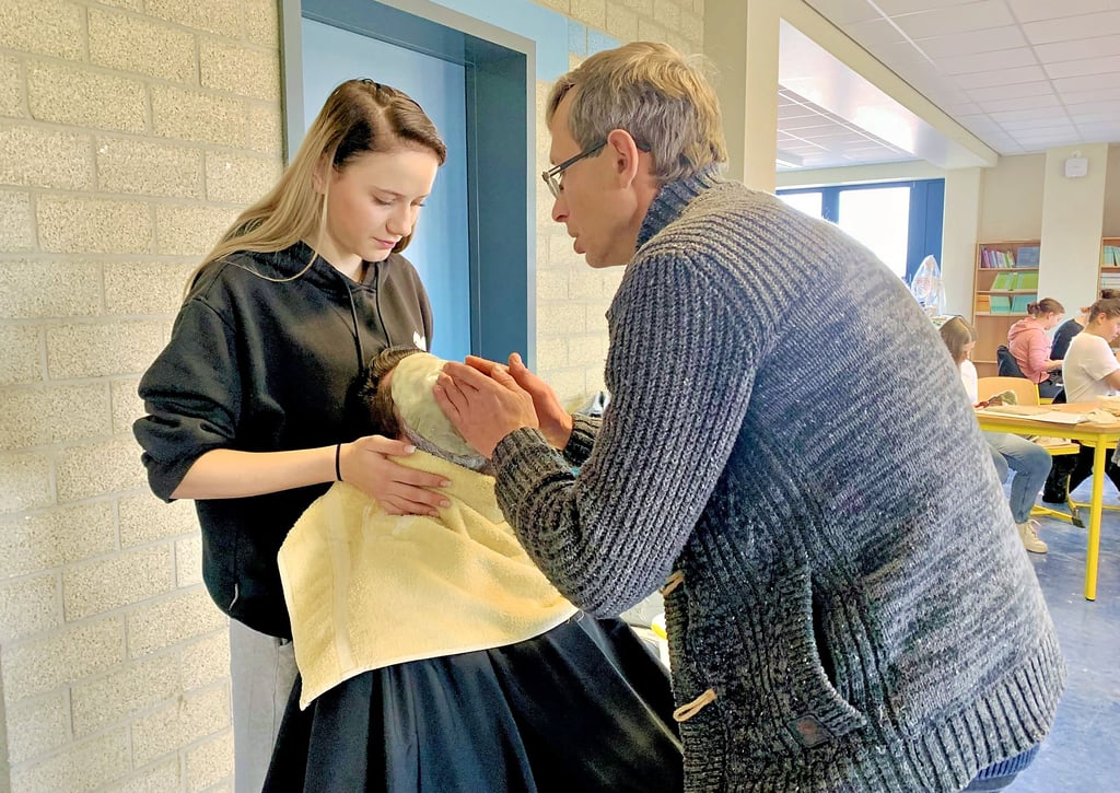 Jenna Steingruber hilft dabei, bei ihrem Mitschüler Jill Braun die Modelliermasse für die Gesichtsmaske aufzutragen. Die Berufsschüler aus Oschersleben wirken am Friedensmonument des Künstlers Marcus Barwitzki mit.