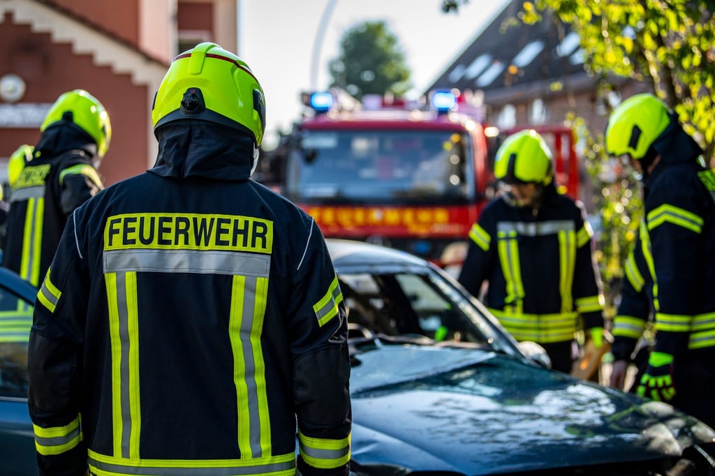 Feuerwehrleute stehen um ein Auto, das einen Unfall gehabt hat.
