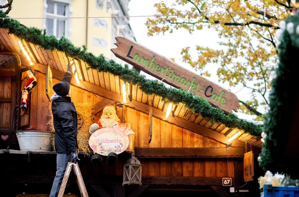 Schausteller Ray Hempen verschraubt mehrere Lampen an einem Stand auf dem Lambertimarkt auf dem Schlossplatz.