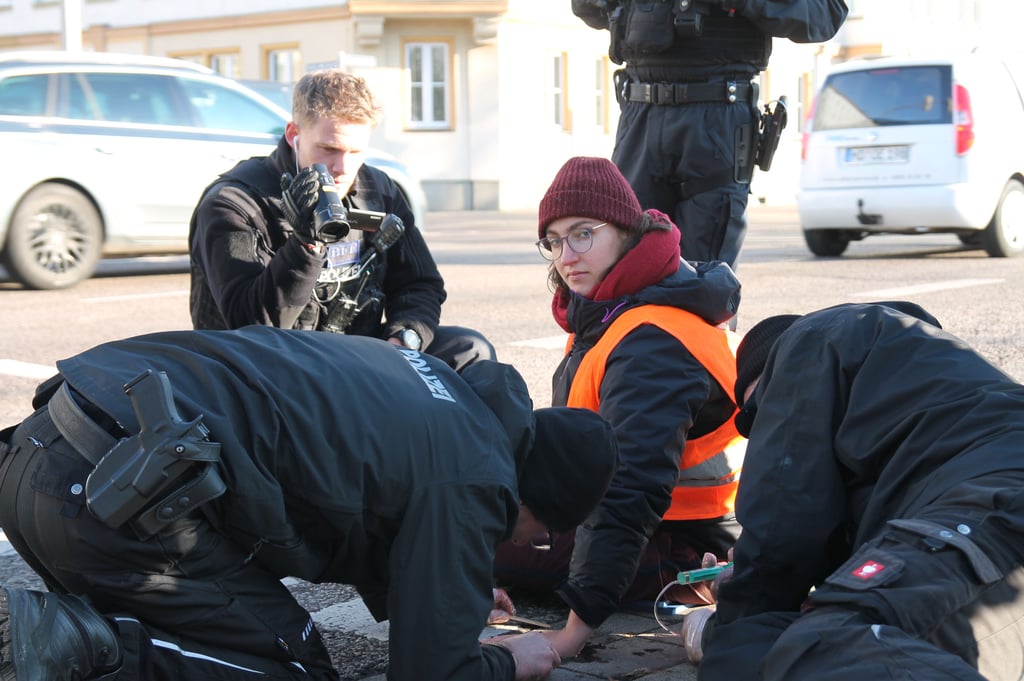 Festgeklebt im Berufsverkehr: Magdeburger Polizisten lösen Klimaaktivisten Pia Osman am Montag vom Straßenbelag ab.