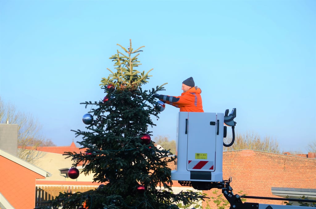 Ein Mitarbeiter des Salzwedeler Wirtschaftshofes schmückt den großen Tannenbaum auf dem Rathausturmplatz mit einer silbernen Kugel.