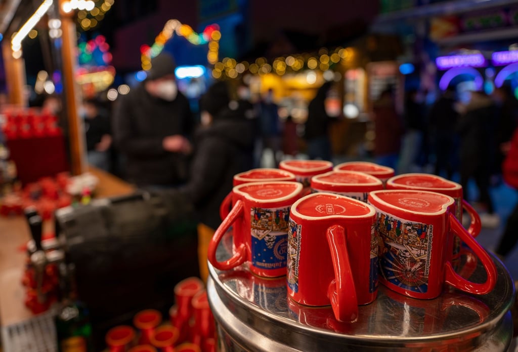 Glühweintassen stehen auf einem Weihnachtsmarkt vor einem Stand auf einem Tisch.