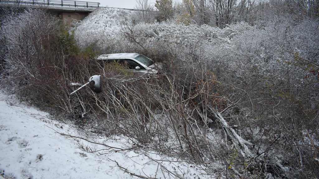 Ein Foto der Polizei zeigt den Unfallwagen, der mitten in einem winterlich verschneiten Gehölz gelandet ist.
