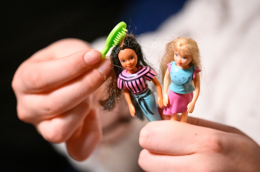 Eine junge Frau kämmt die Haare von zwei der größeren Polly Pocket Puppen.