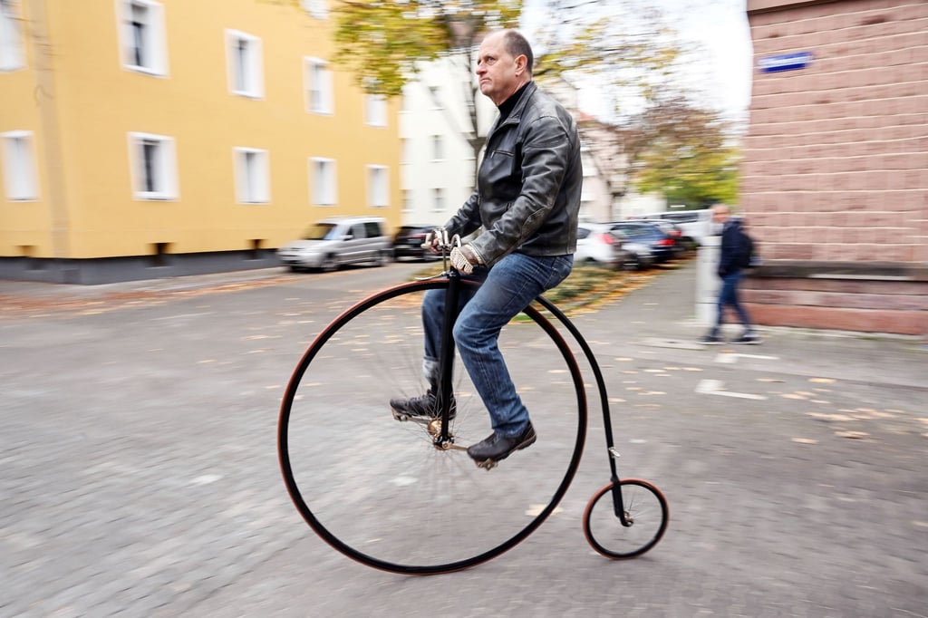 Tobias Krieger fährt mit einem Hochrad eine Straße entlang. Der Karlsruher ist mit dem Hochrad unterwegs - wie die Menschen am Ende des 19. Jahrhunderts. Heute zählt er zu wenigen, die das noch können.