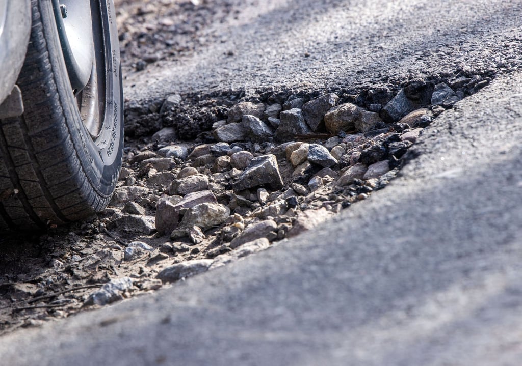 Ein Auto fährt durch ein Schlagloch: Immer mehr Unternehmen klagen über die teilweise marode Straßen in Deutschland.