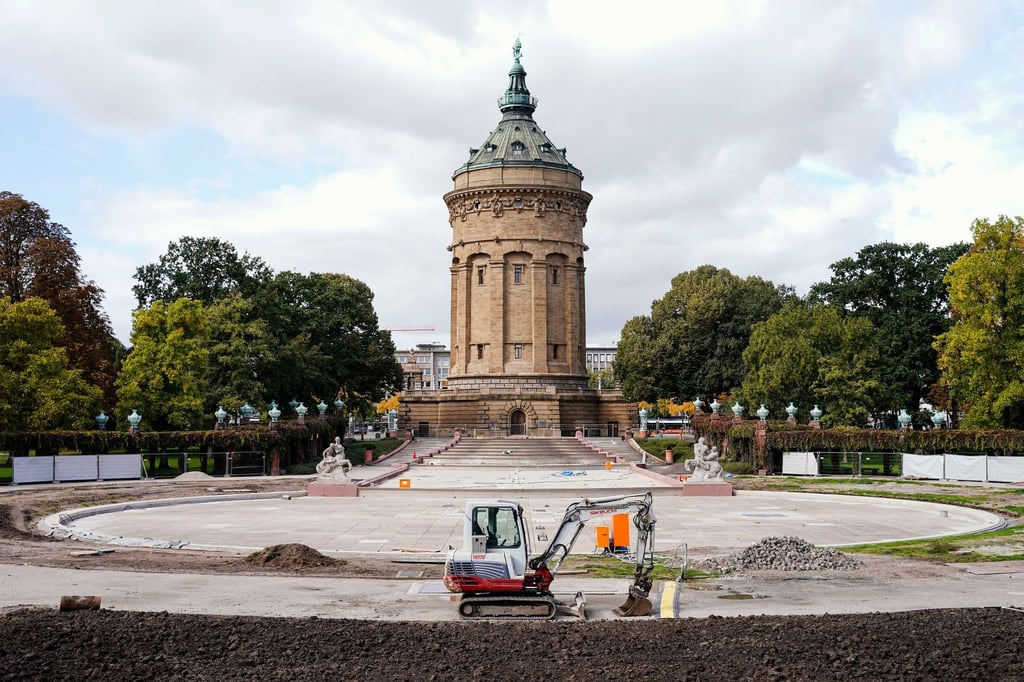 Ein Bagger steht vor der trockengelegten Fontänenanlage von Mannheims Wasserturm.
