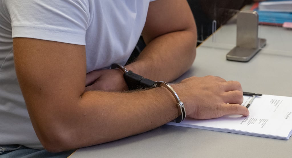 Ein Mann sitzt in Handschellen vor Gericht - selbst Haftstrafen werden nach einigen Jahren aus dem polizeilichen Führungszeugnis gelöscht.