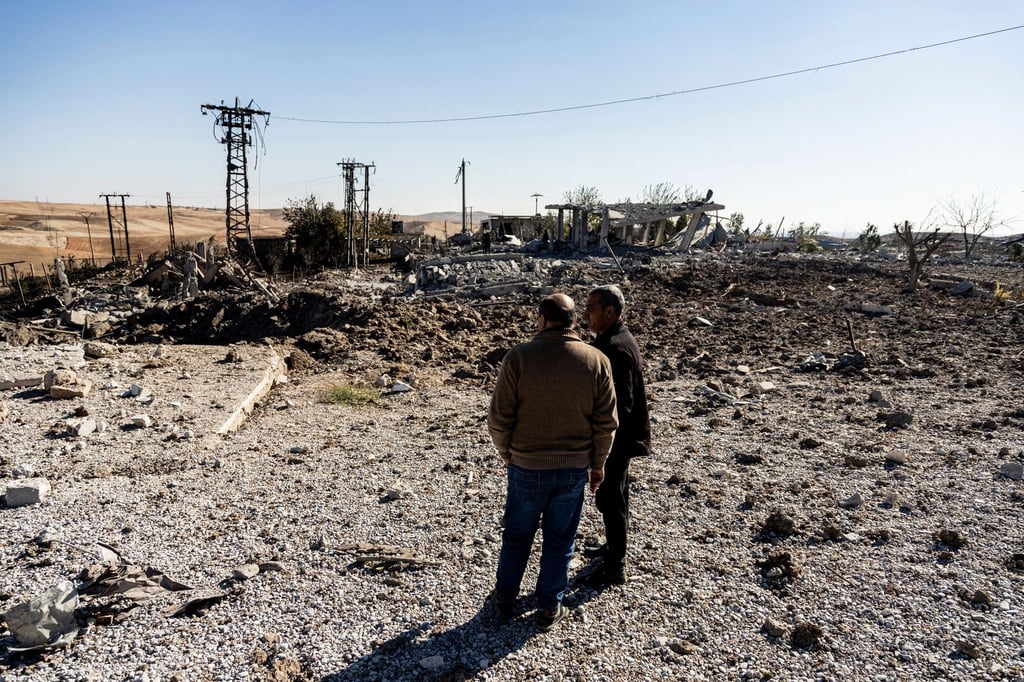 Zwei Männer begutachten Schäden in einem Gebiet um ein Elektrizitätswerk in Nordsyrien nach türkischen Luftangriffen.