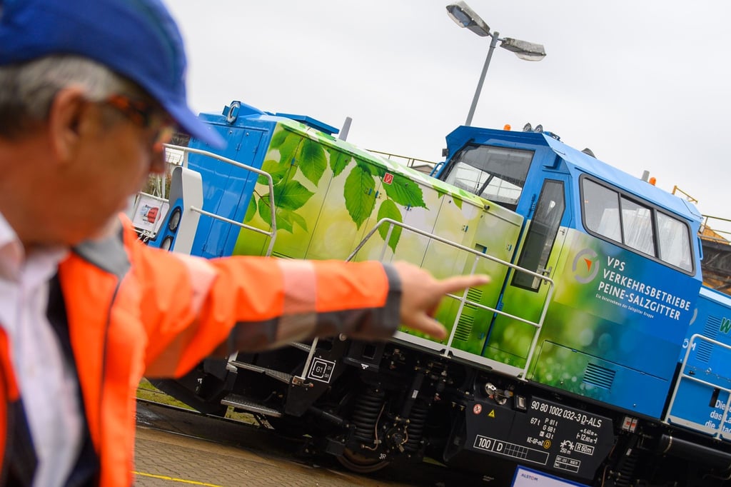 Alstom-Werksleiter Jörg Neubauer zeigt auf eine Rangierlok mit Wasserstoffantrieb.