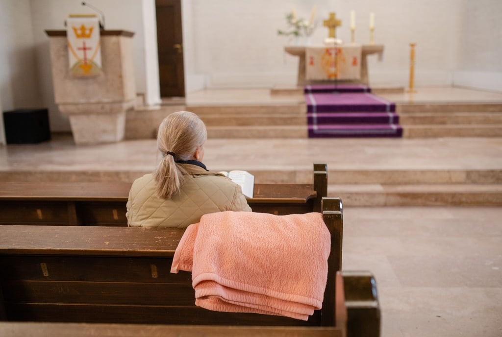 Eine Frau sitzt mit einer Decke in der Christuskirche.