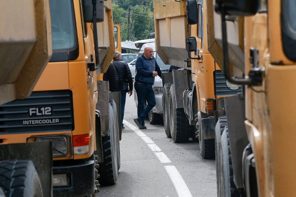 Zwei serbische Männer stehen neben einer Straße, die zum Grenzübergang Jarinje im Norden des Kosovo führt.